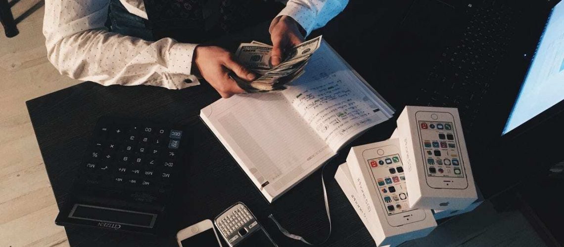 person-counting-money-with-smartphones-in-front-on-desk-210990